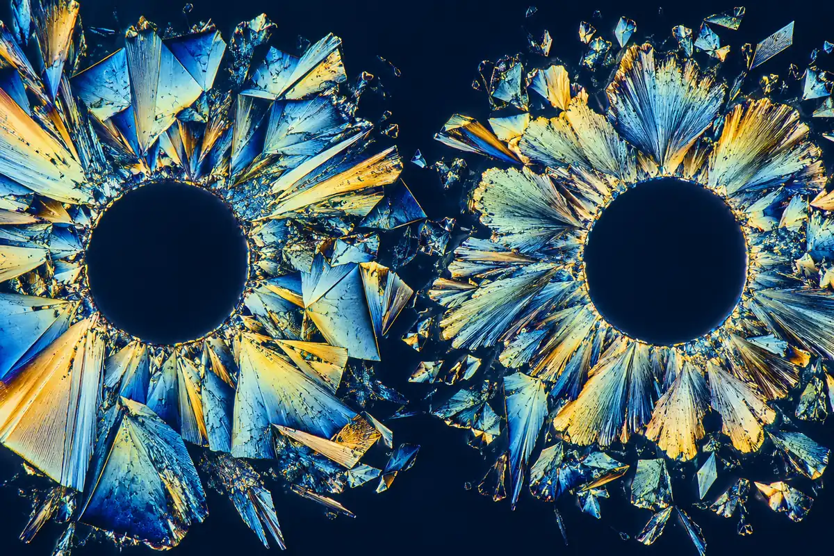 Two separate crystal formations surround dark circular centres in blue and gold light.